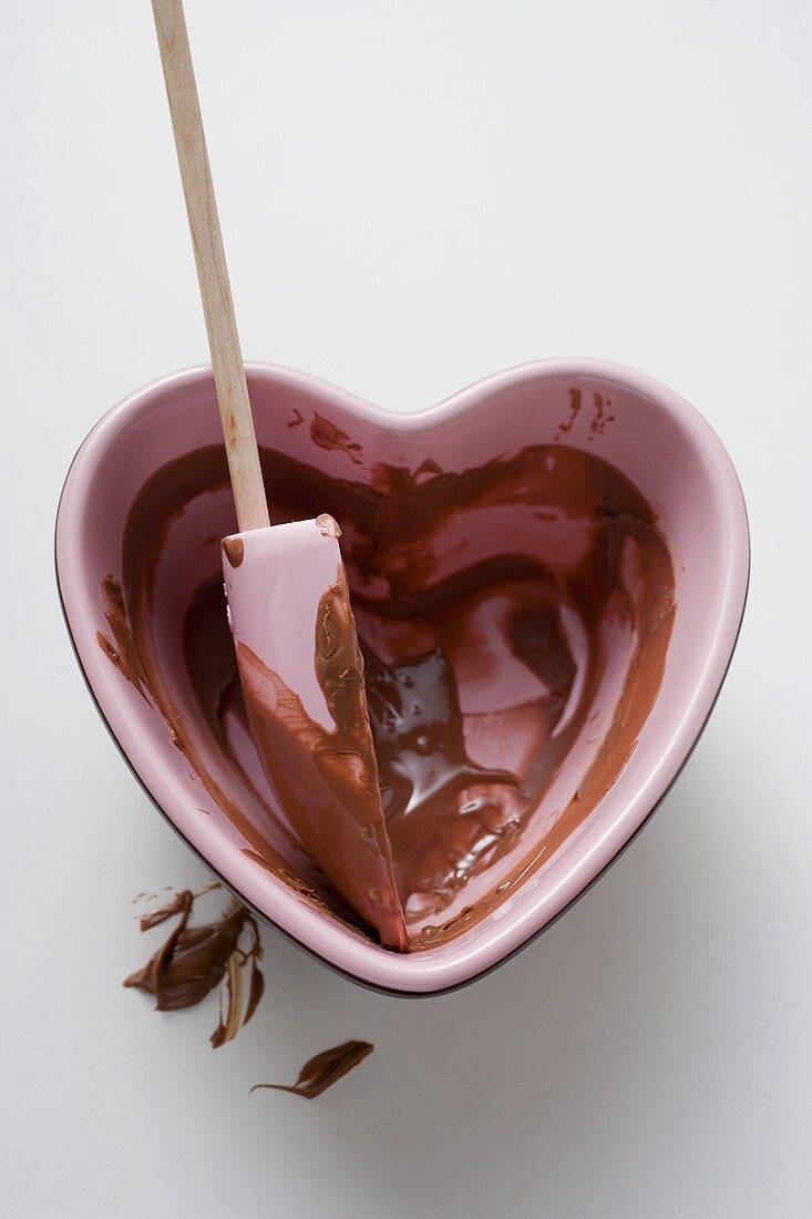 Heart-shaped bowl with mixing spoon & remains of chocolate sauce