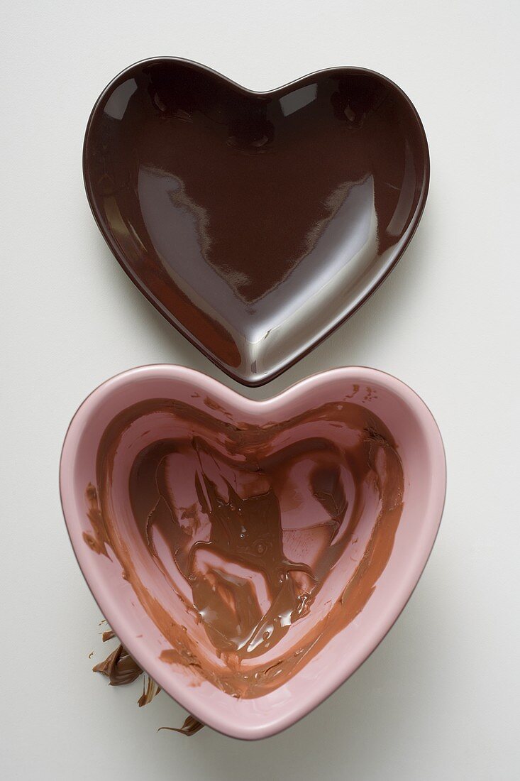 Two heart-shaped bowls, one with remains of chocolate sauce