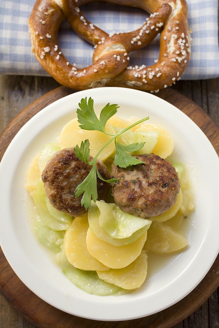 Burgers on potato and cucumber salad with pretzel