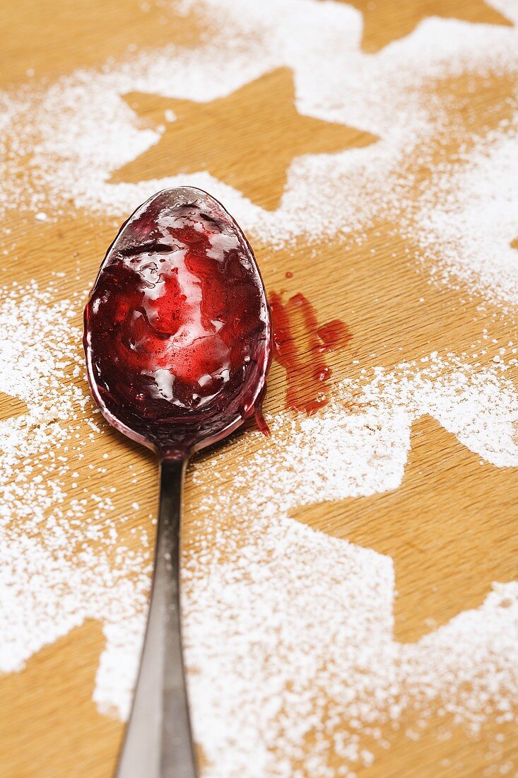 Star shapes outlined in icing sugar and spoon with jam