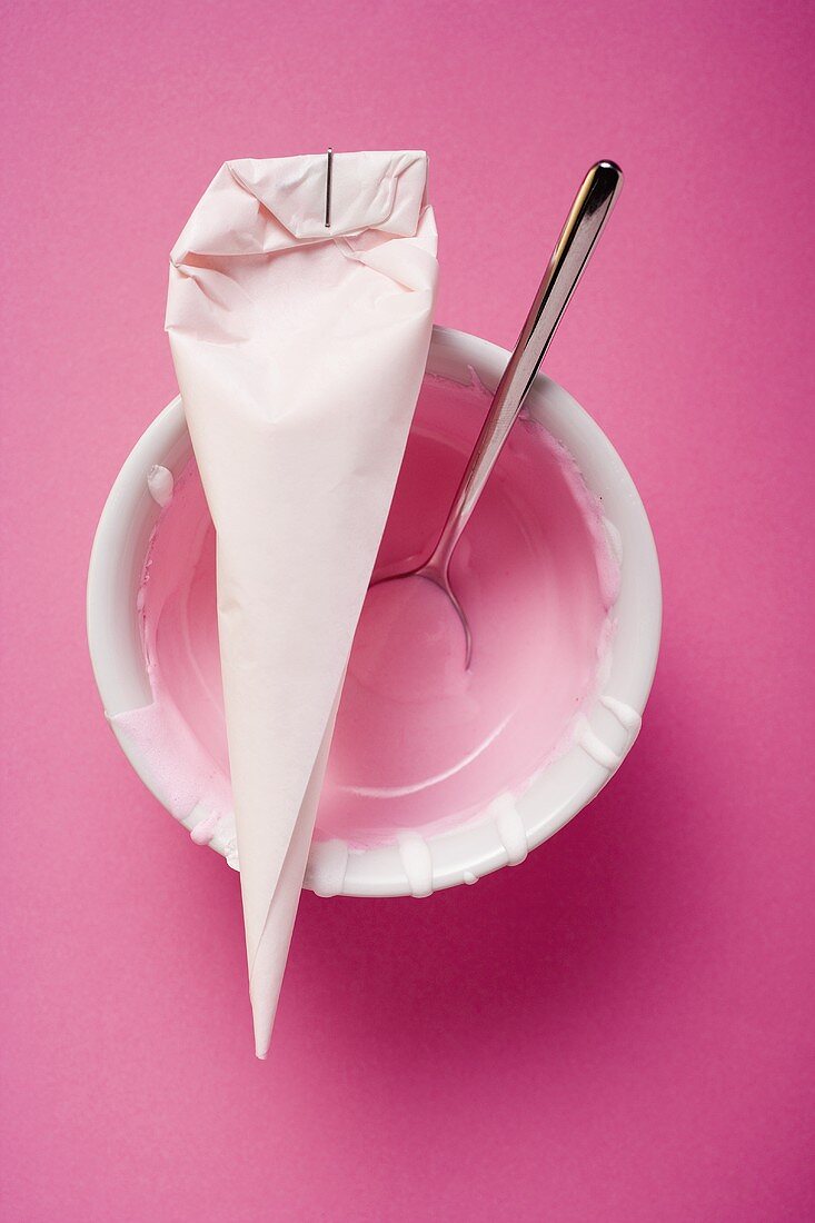 Spritztüte mit rosa Glasur und Löffel