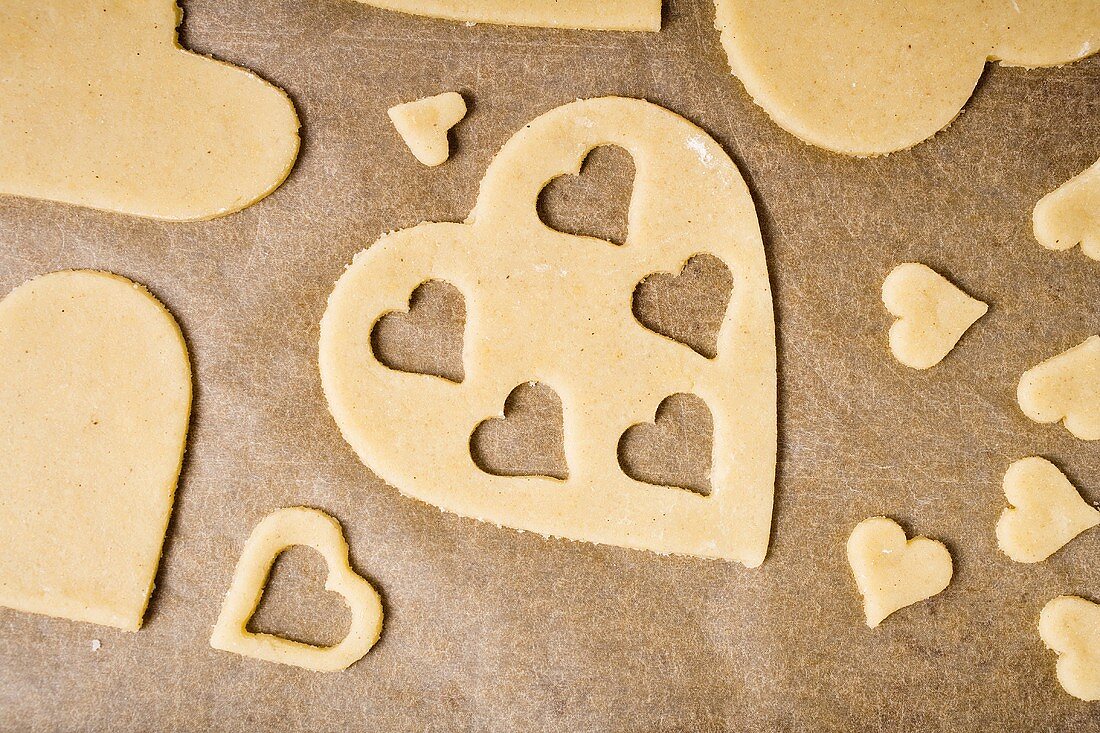 Cut-out heart-shaped biscuits on baking parchment