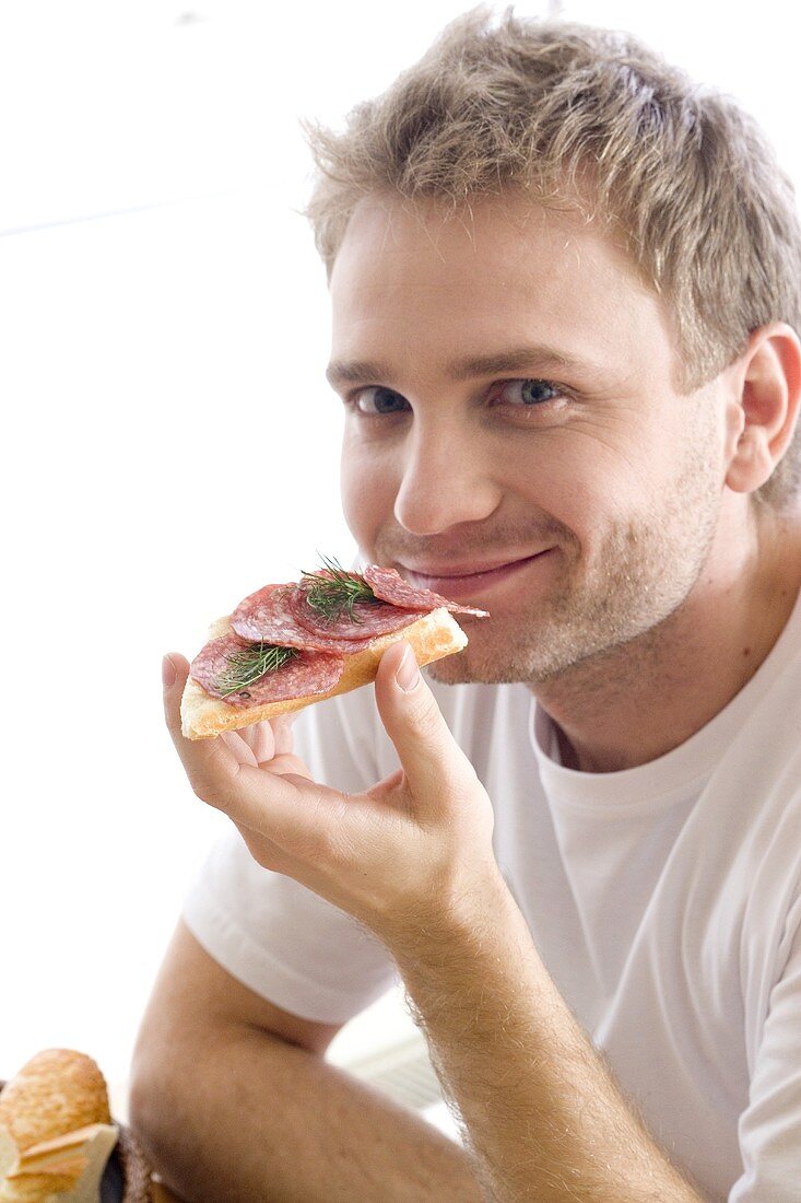 Young man with open salami sandwich