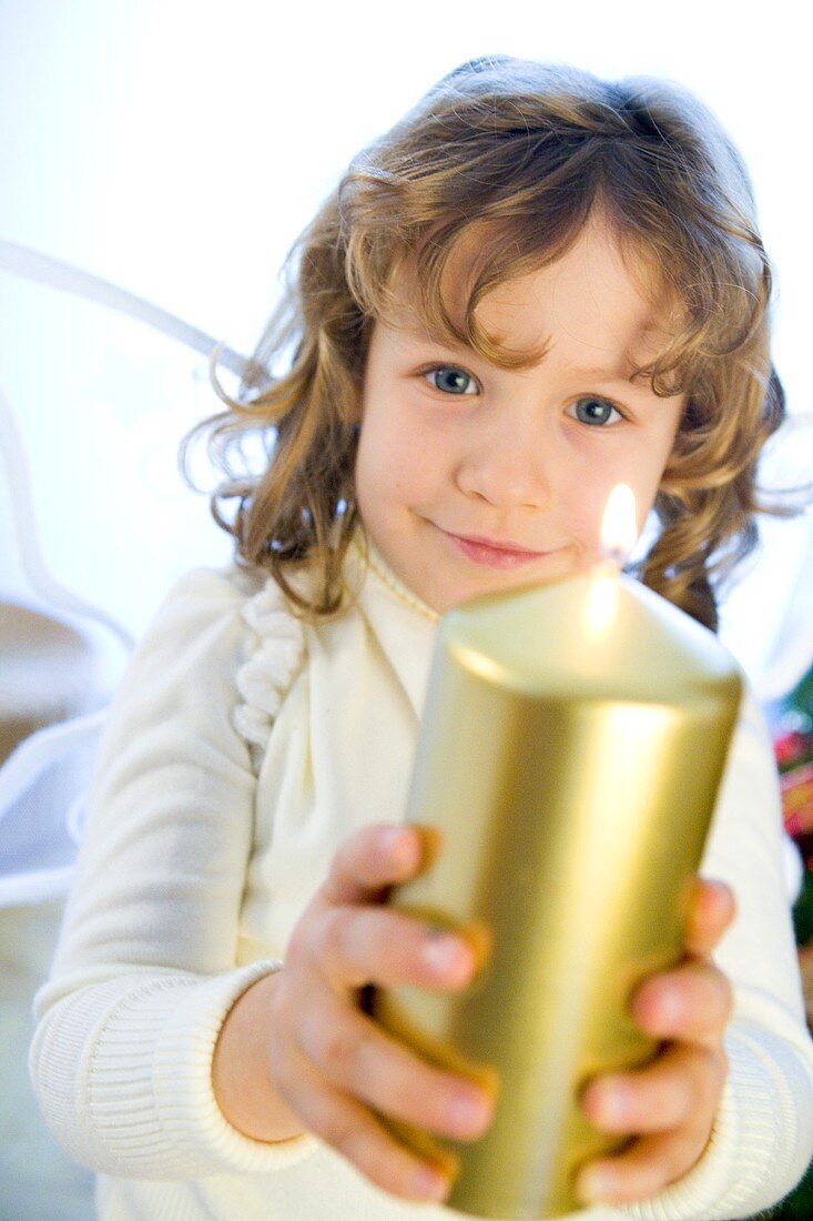 Girl dressed as angel with golden candle