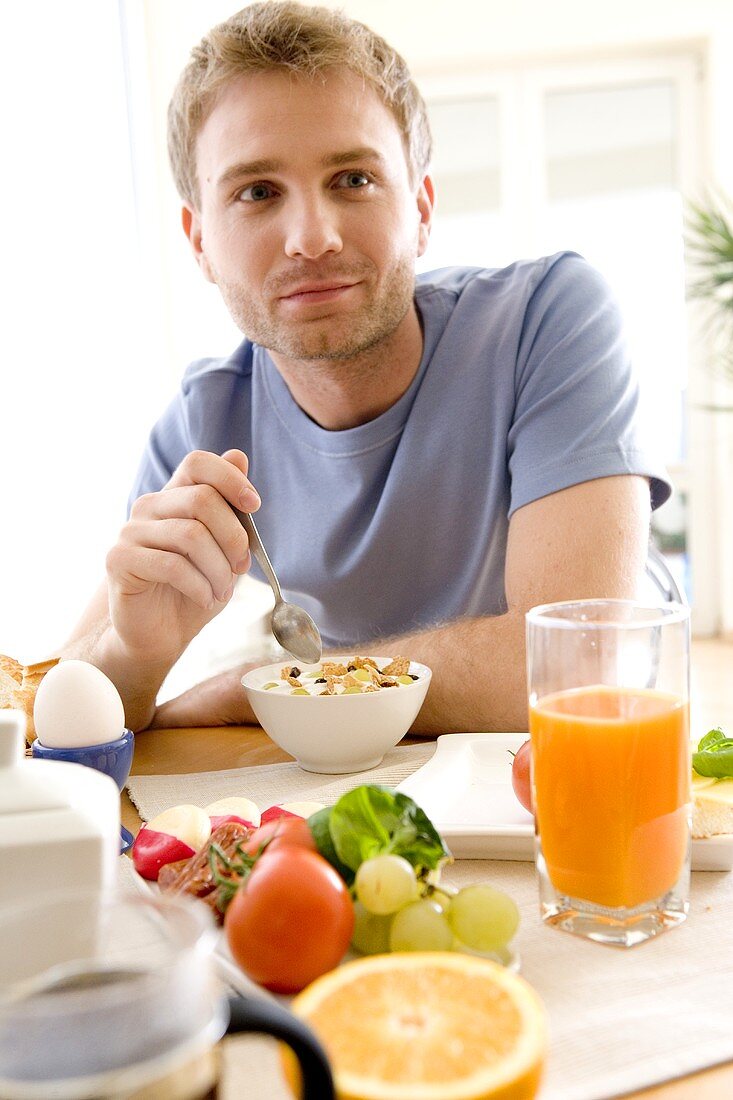 Junger Mann isst Joghurtmüsli zum Frühstück