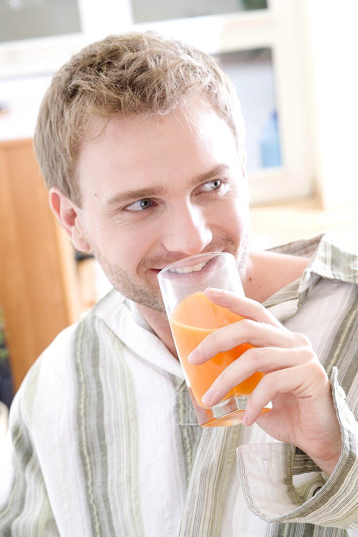 Junger Mann trinkt aus einem Saftglas