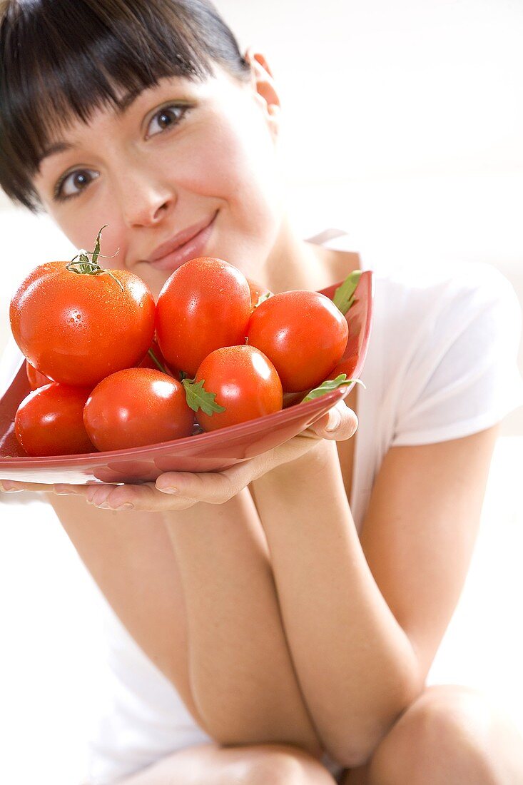 Junge Frau hält Schale mit Tomaten