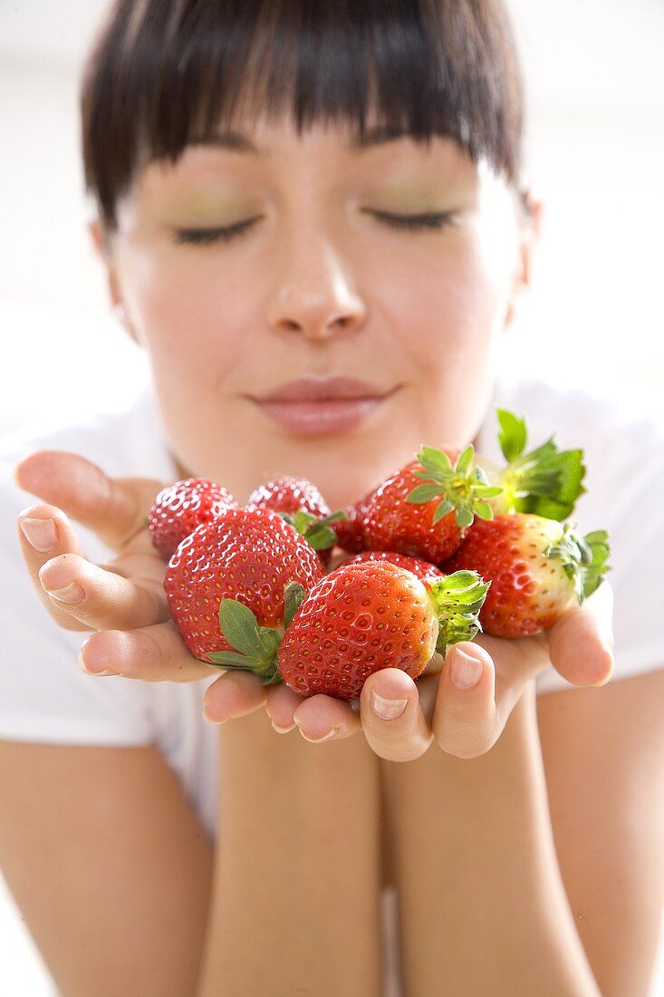 Young woman holding fresh strawberries