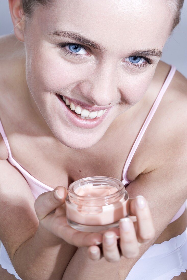 Young woman with a jar of face cream in her hands