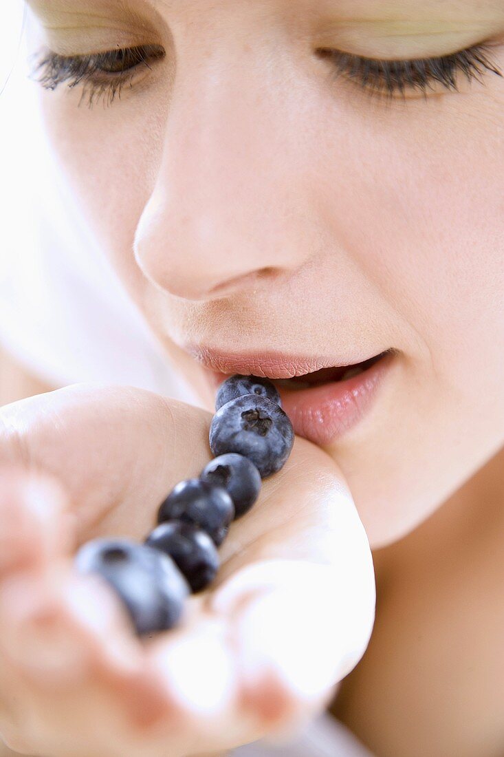 Young woman with a row of blueberries on her hand