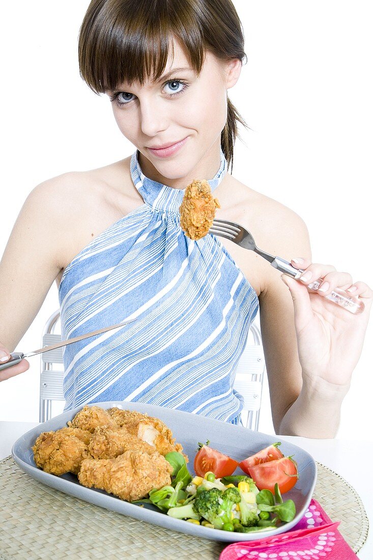 Young woman eating breaded chicken