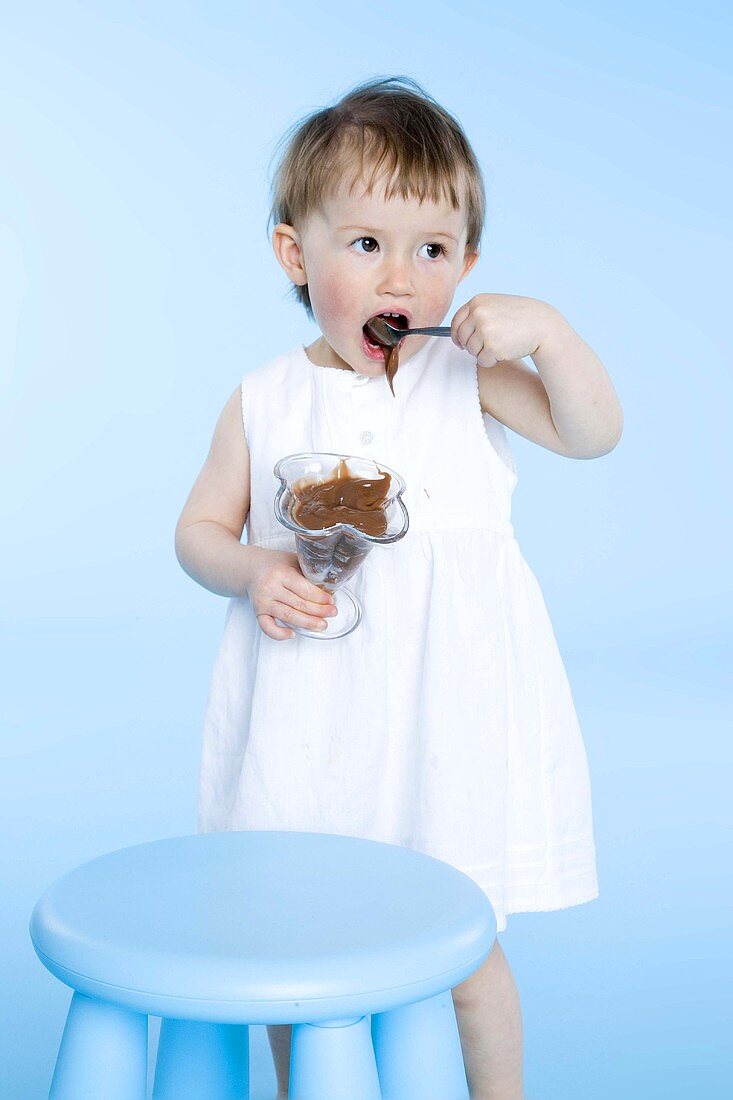 Small girl eating chocolate pudding