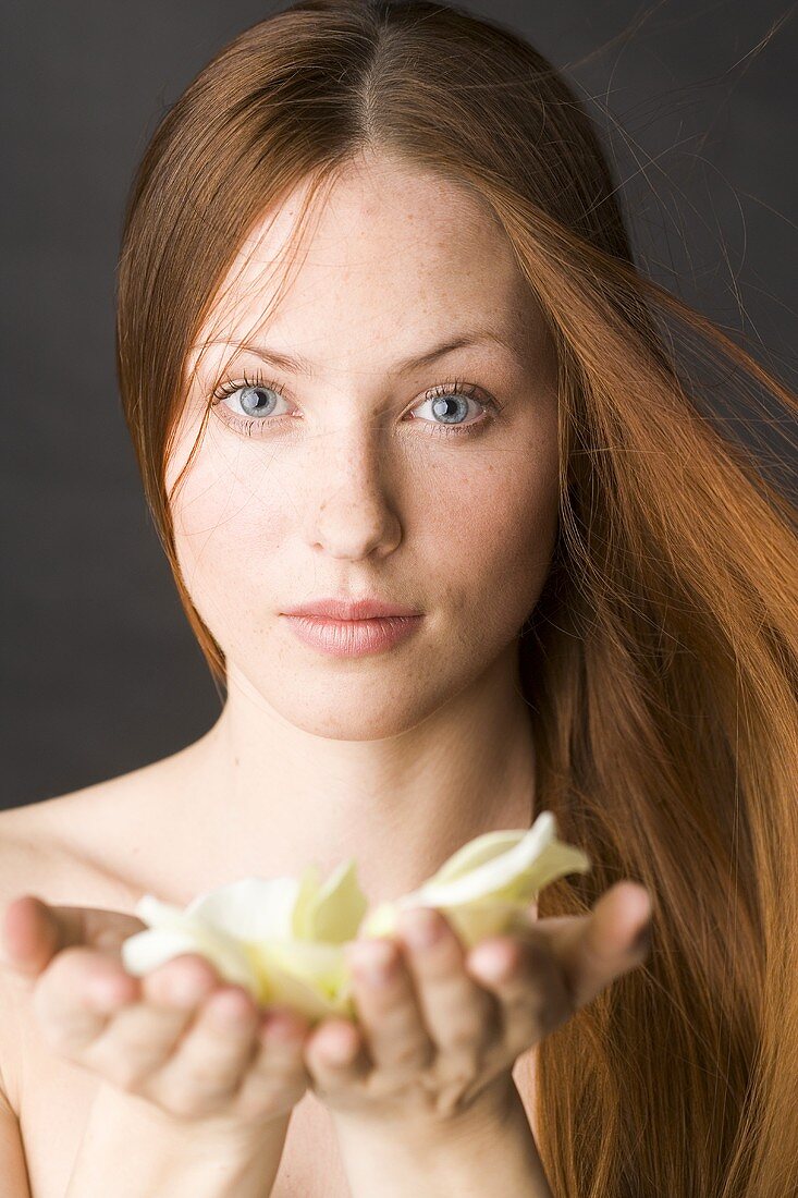 Red-haired woman with white rose petals