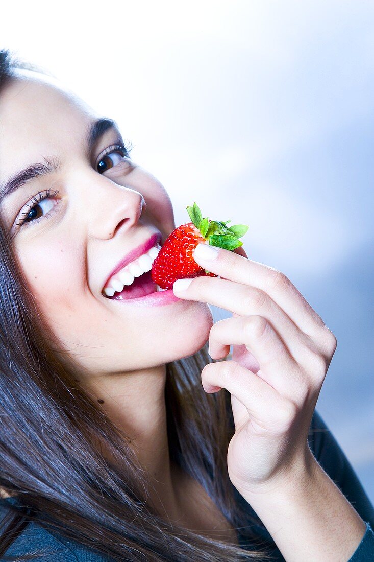Junge Frau beisst in eine Erdbeere