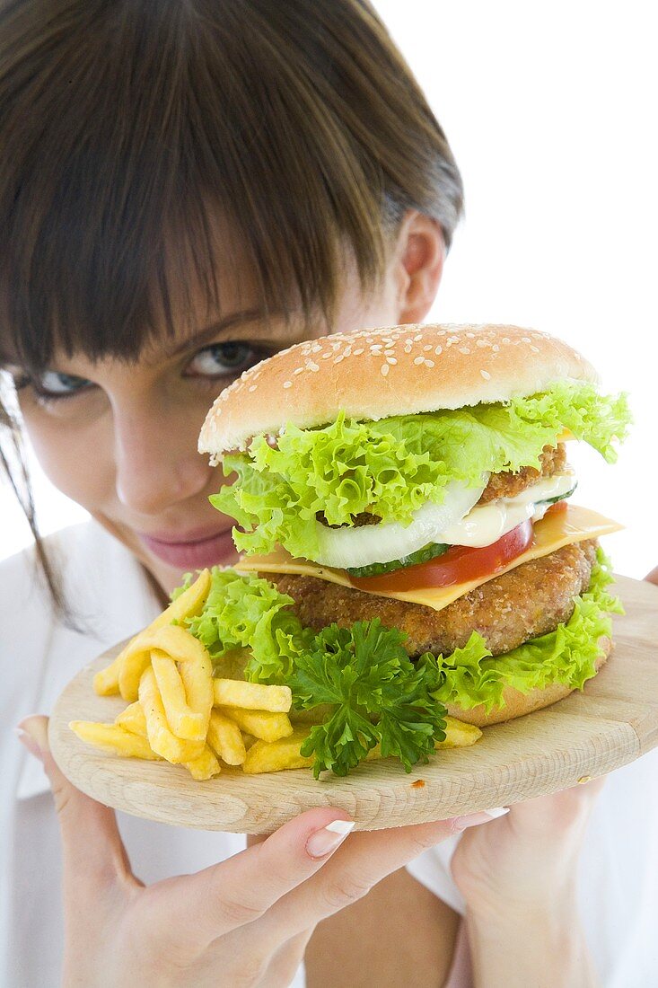 Junge Frau versteckt sich hinter einem Riesenhamburger