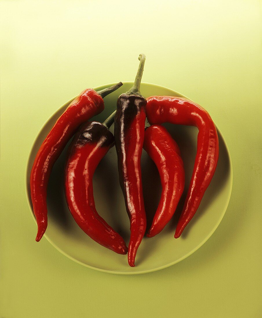Five red chillies on green plate