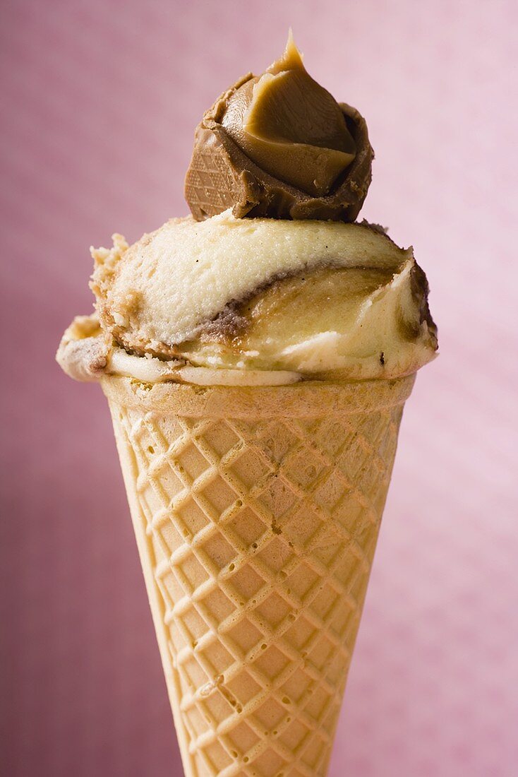 Caramel ice cream in wafer cone against pink background