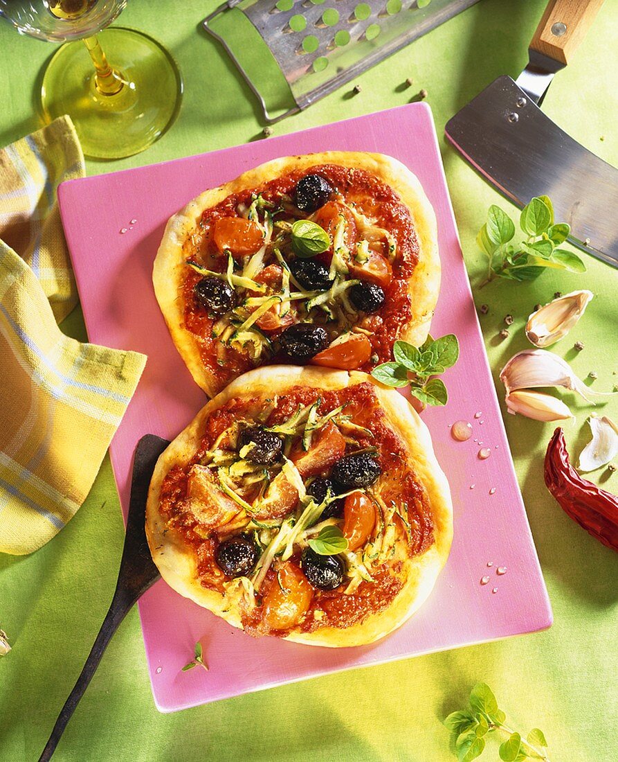 Two pizzas with tomato sauce and black olives