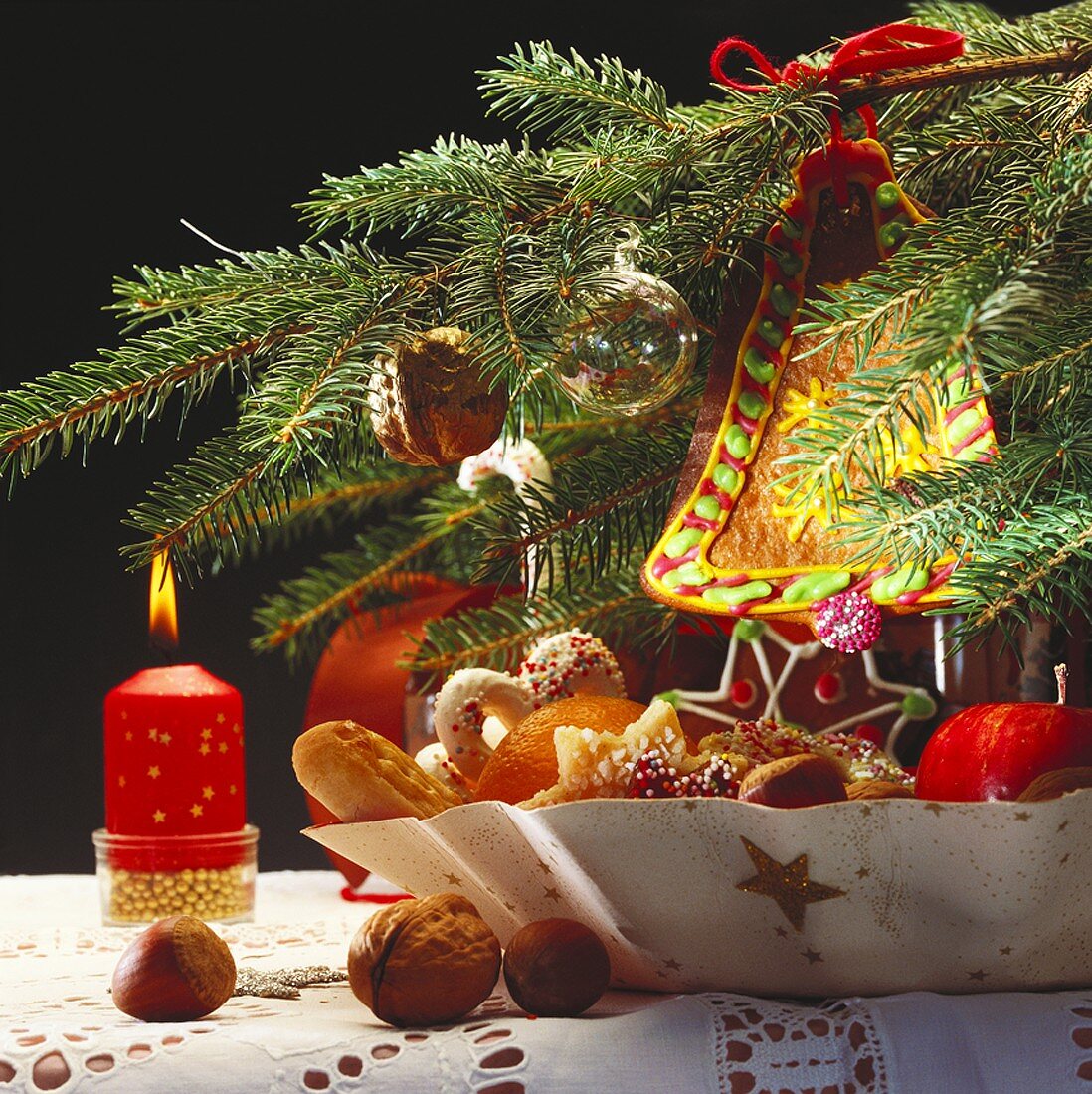 Plate of biscuits, candle, fir branch with tree ornaments