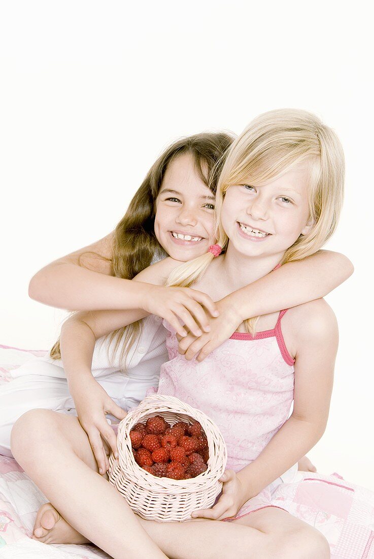 Zwei Mädchen mit Himbeeren im Körbchen