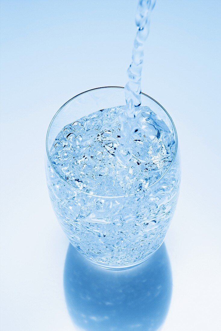 Wasser wird in ein Glas eingeschenkt