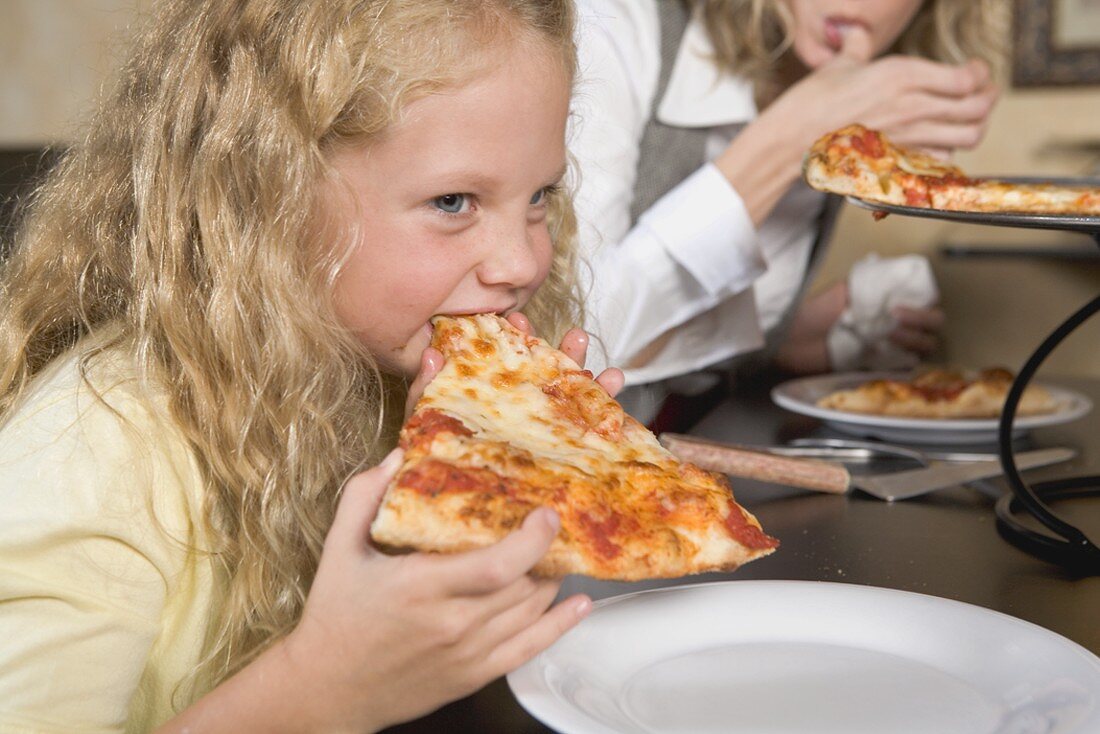 Blond girl eating a slice of pizza