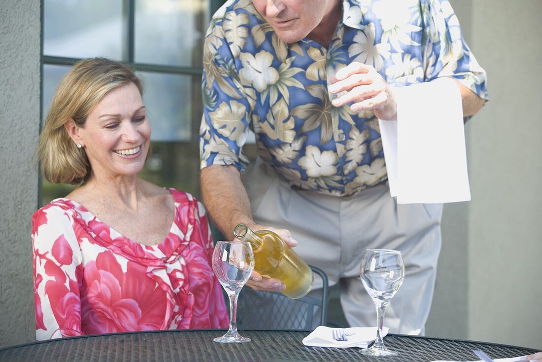 Man pouring white wine for woman
