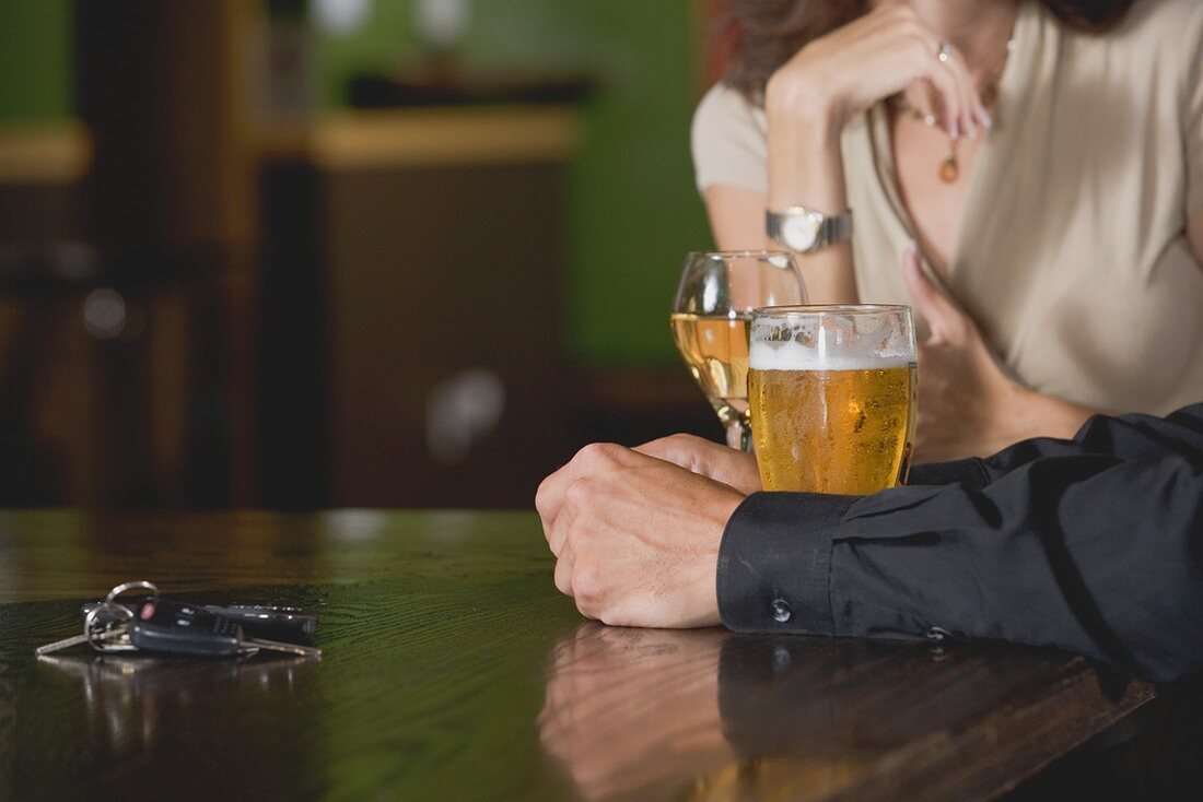 Mann und Frau mit Bier und Wein an der Bar; Autoschlüssel