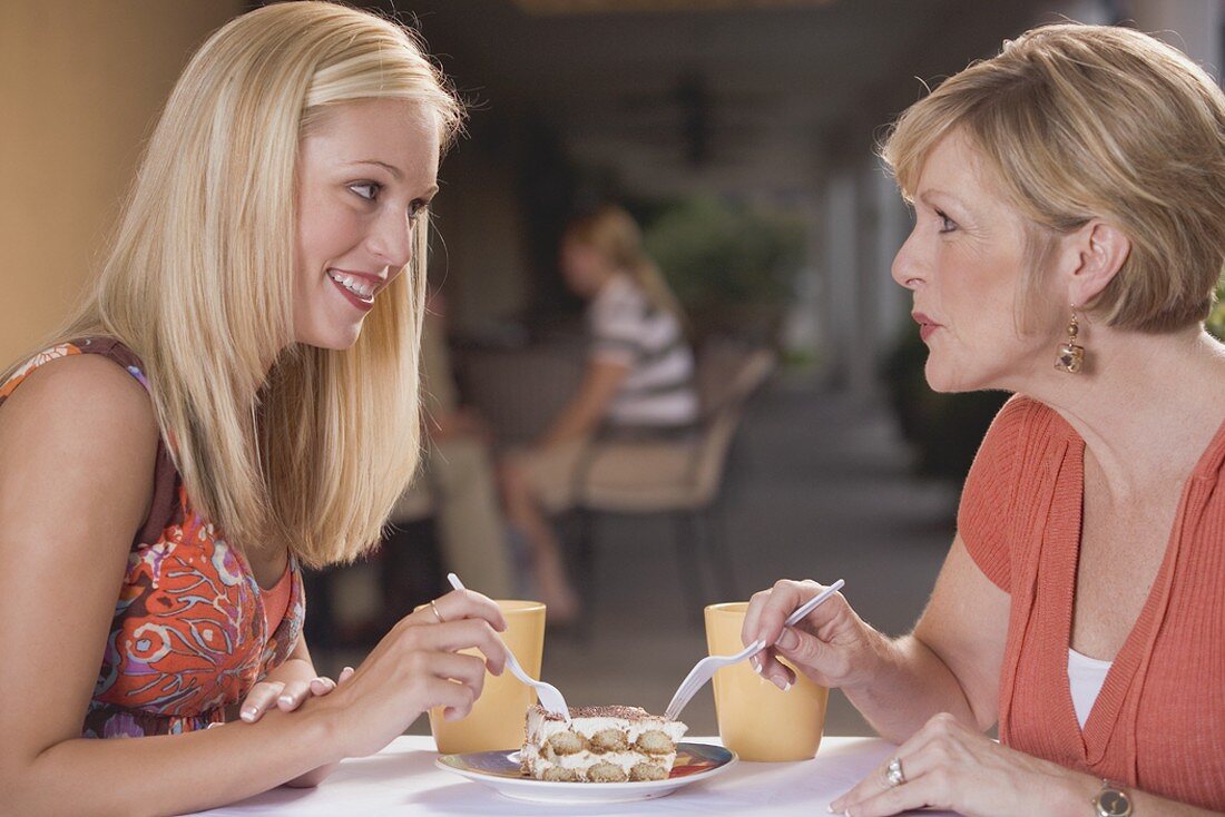 Zwei Frauen in einem Café teilen sich ein Stück Tiramisu