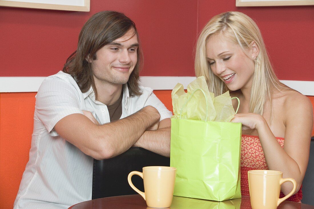 Girl in café opening present from young man
