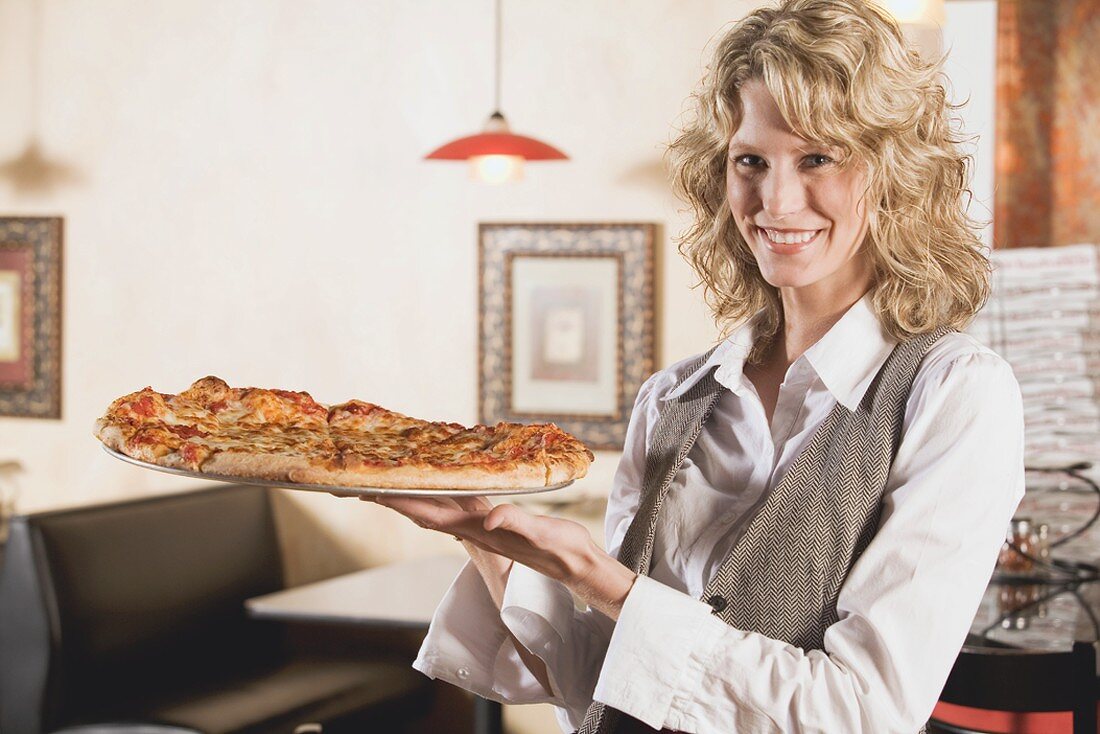 Blonde Frau hält eine Pizza