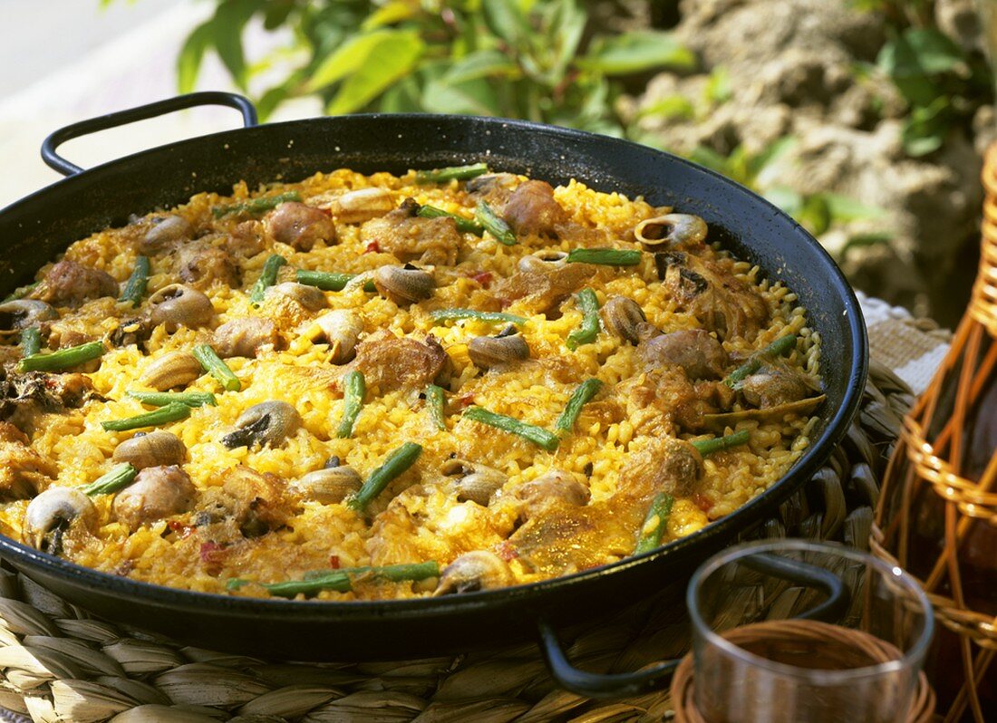 Paella (rice dish) with meat, vegetables and snails