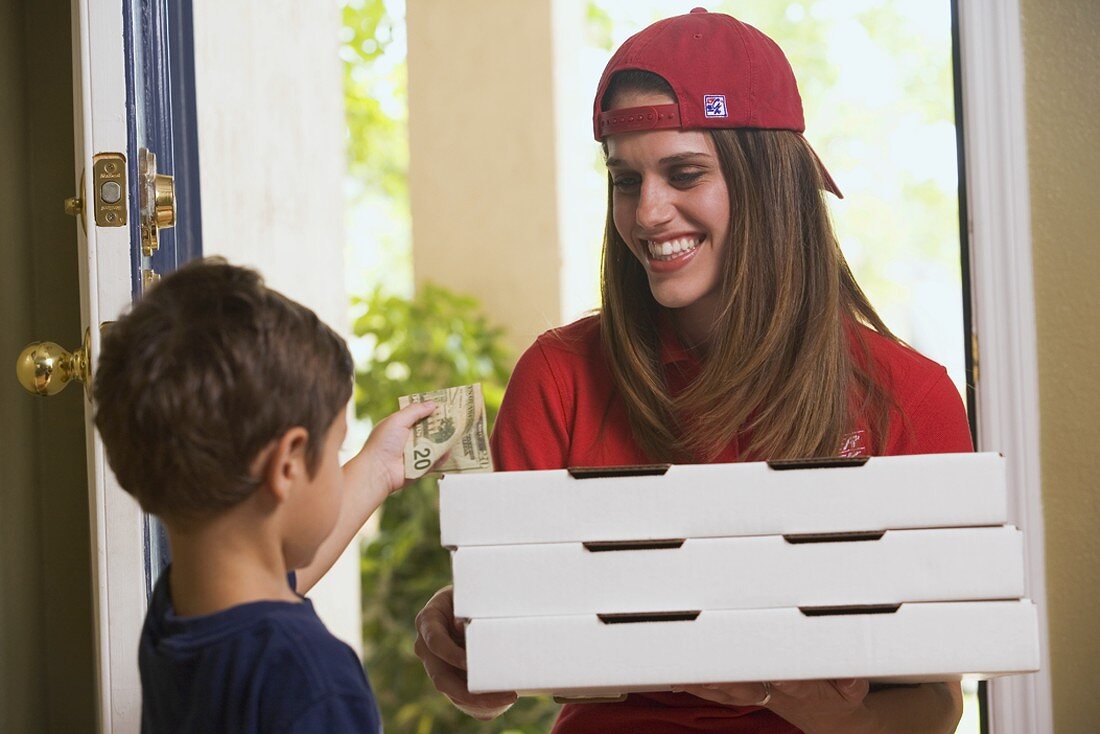 A boy paying a pizza delivery girl