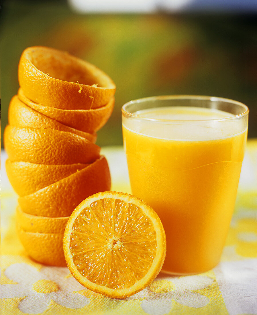 Ein Glas Orangensaft mit ausgepressten Orangenschalen