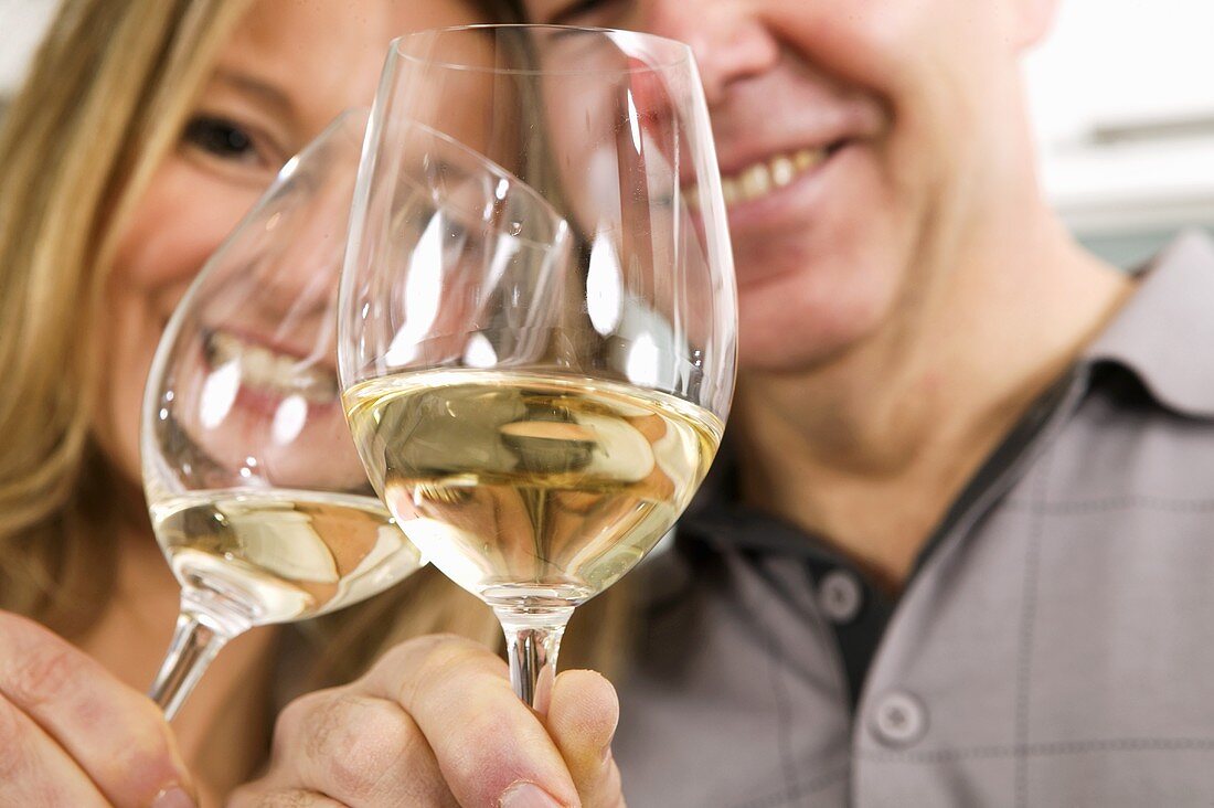 Mann und Frau stossen mit Weißwein an