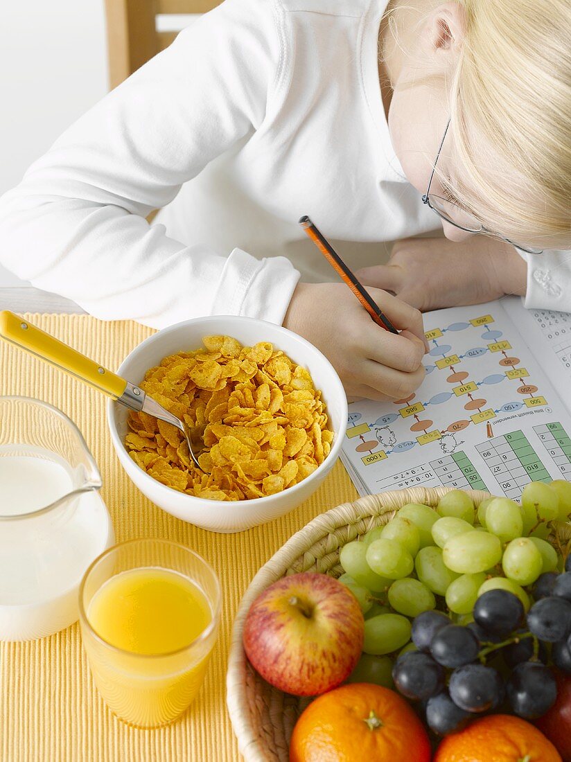 Mädchen mit Schulheft vor gesundem Frühstück