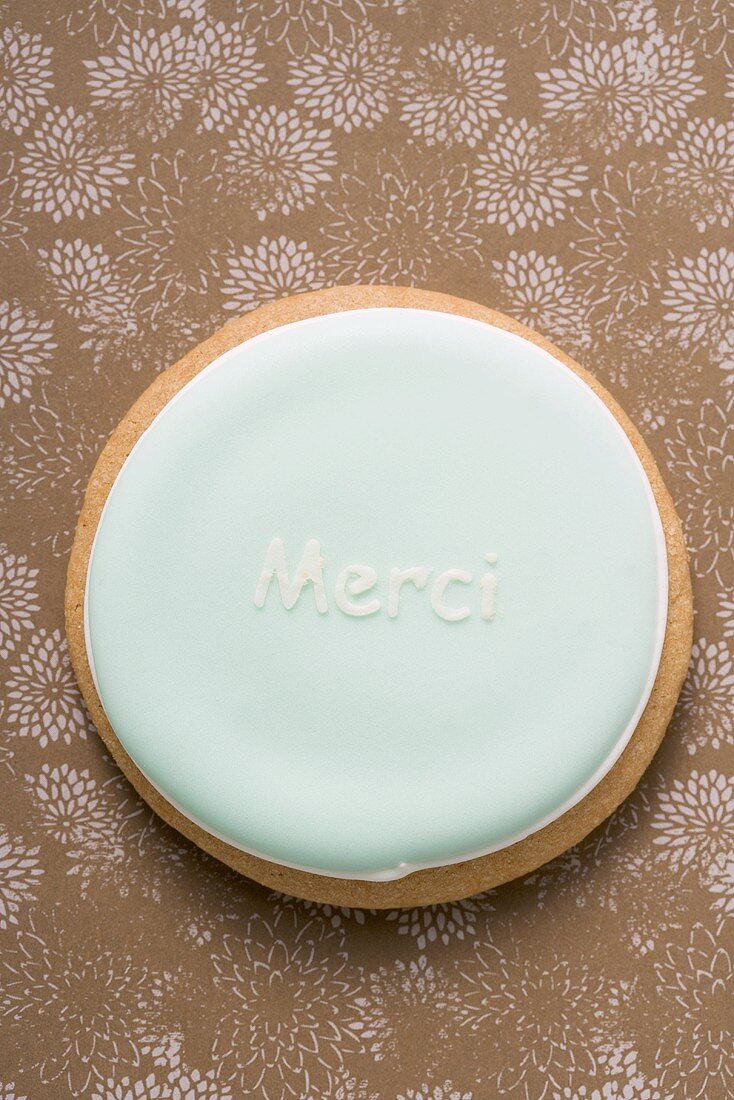 A pastel-coloured biscuit with the word 'Merci'