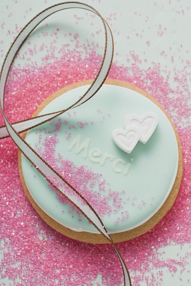 A pastel-coloured biscuit with the word 'Merci'