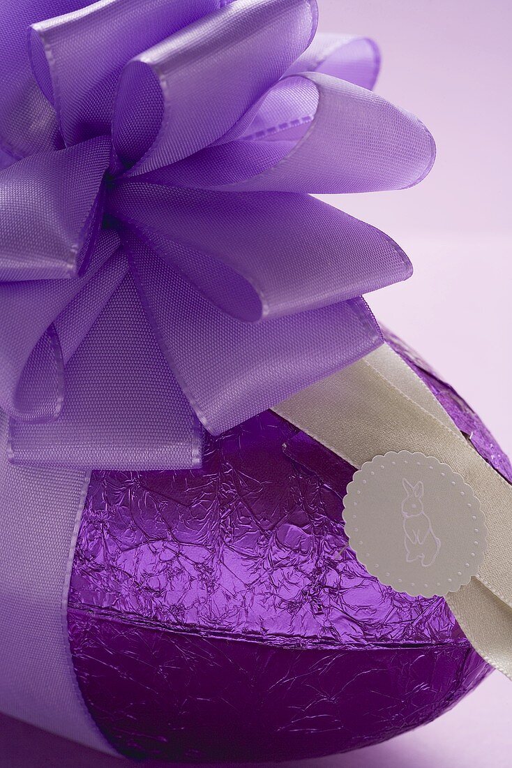 A chocolate Easter egg in purple foil with purple bow