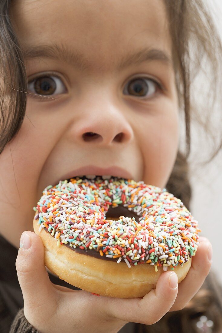 Mädchen beisst in bunten Donut