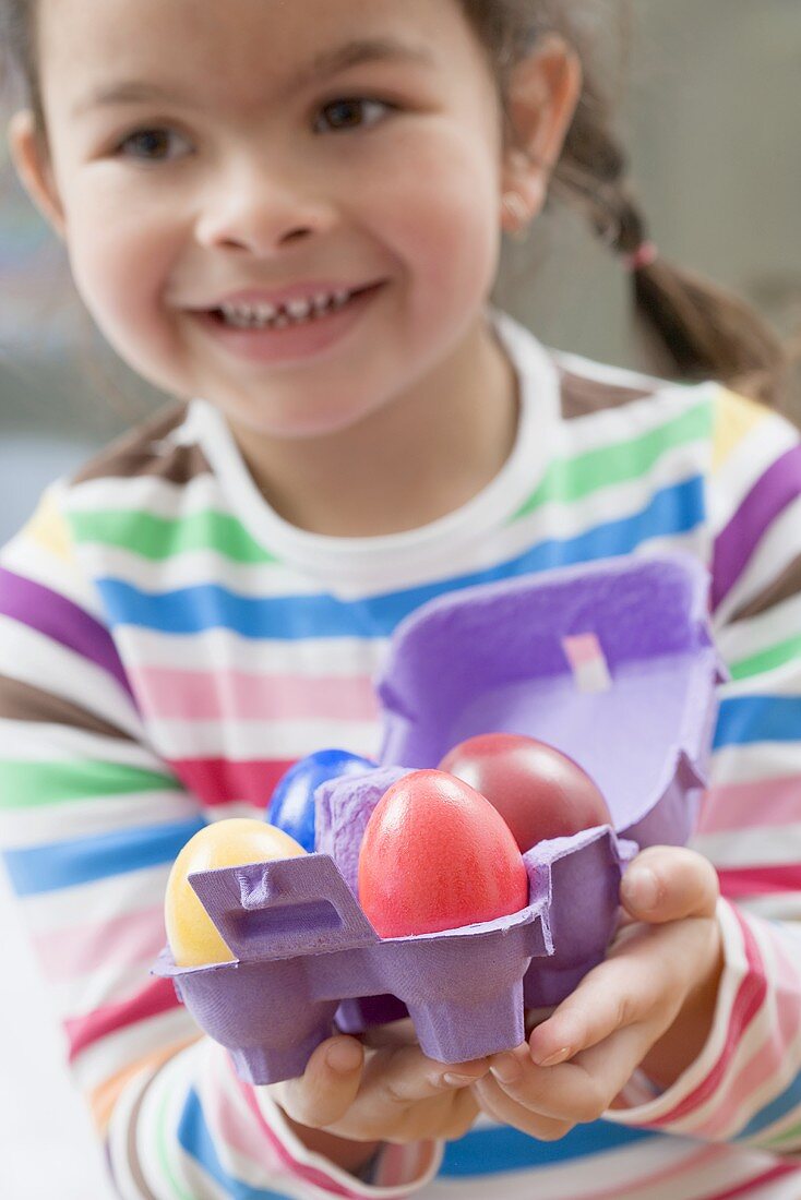 Girl with coloured Easter eggs in an egg box