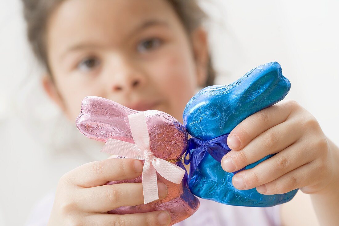 Mädchen mit zwei verpackten Schokoosterhasen