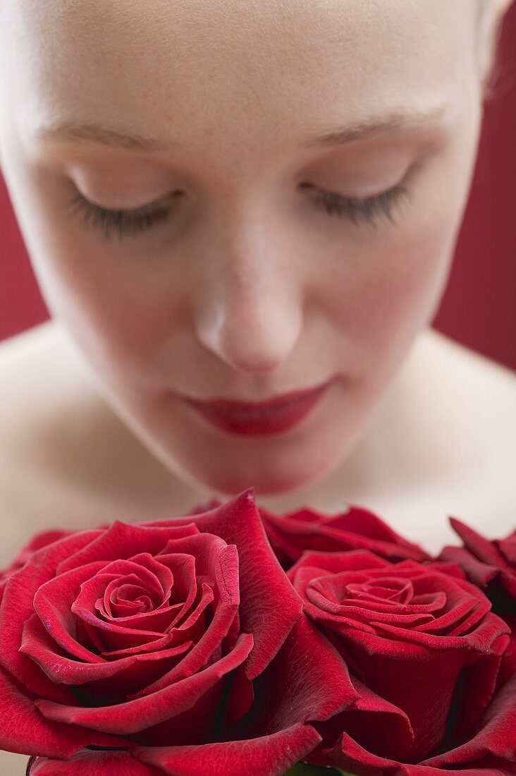 Young woman smelling red roses