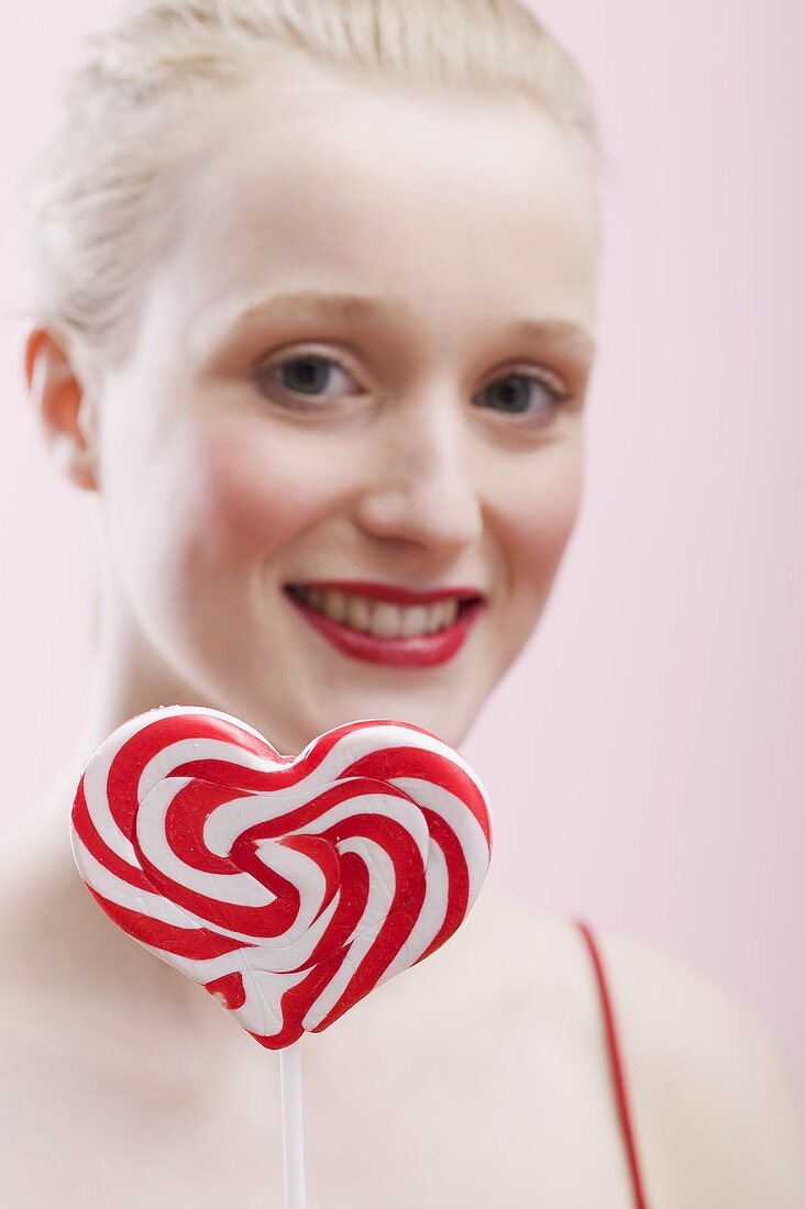 Young woman holding a heart-shaped lollipop
