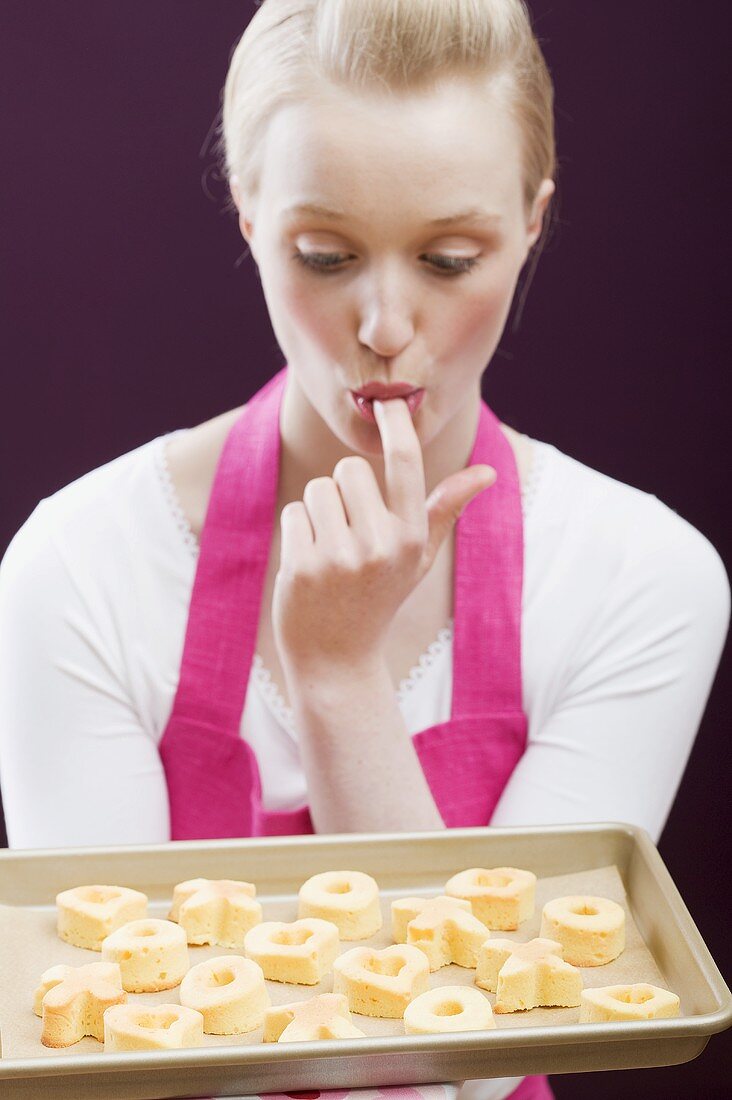 Junge Frau mit einem Backblech frisch gebackenen Keksen