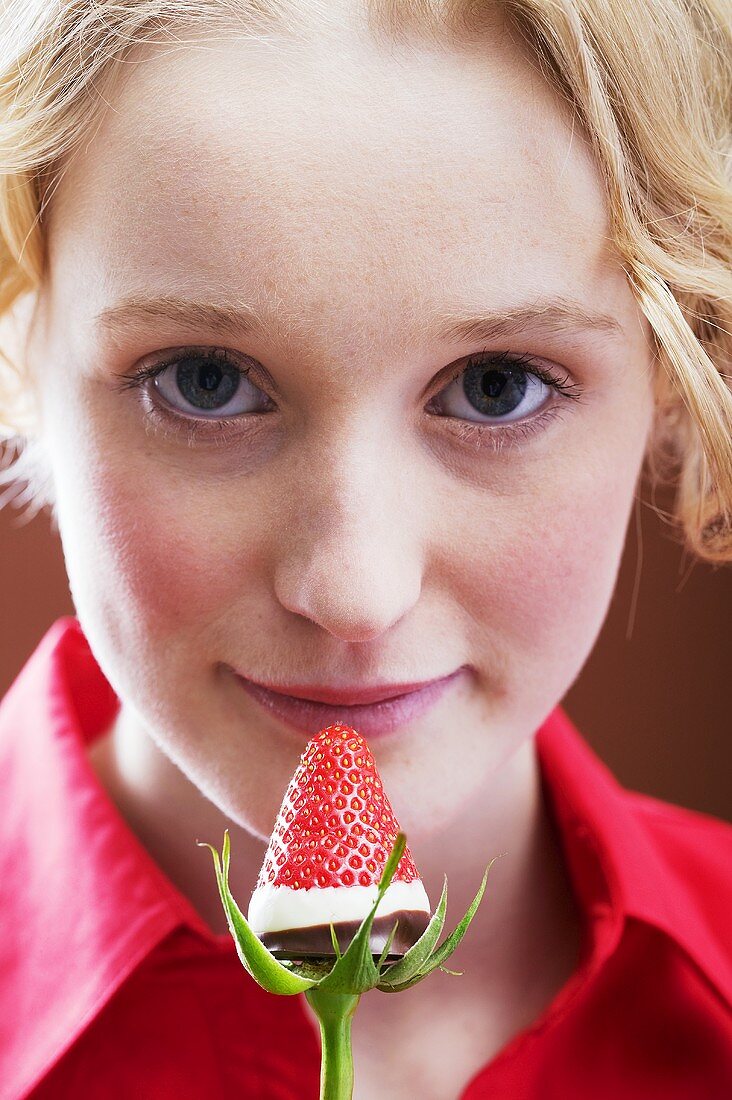 Junge Frau mit einer in Schokolade getauchte Erdbeere
