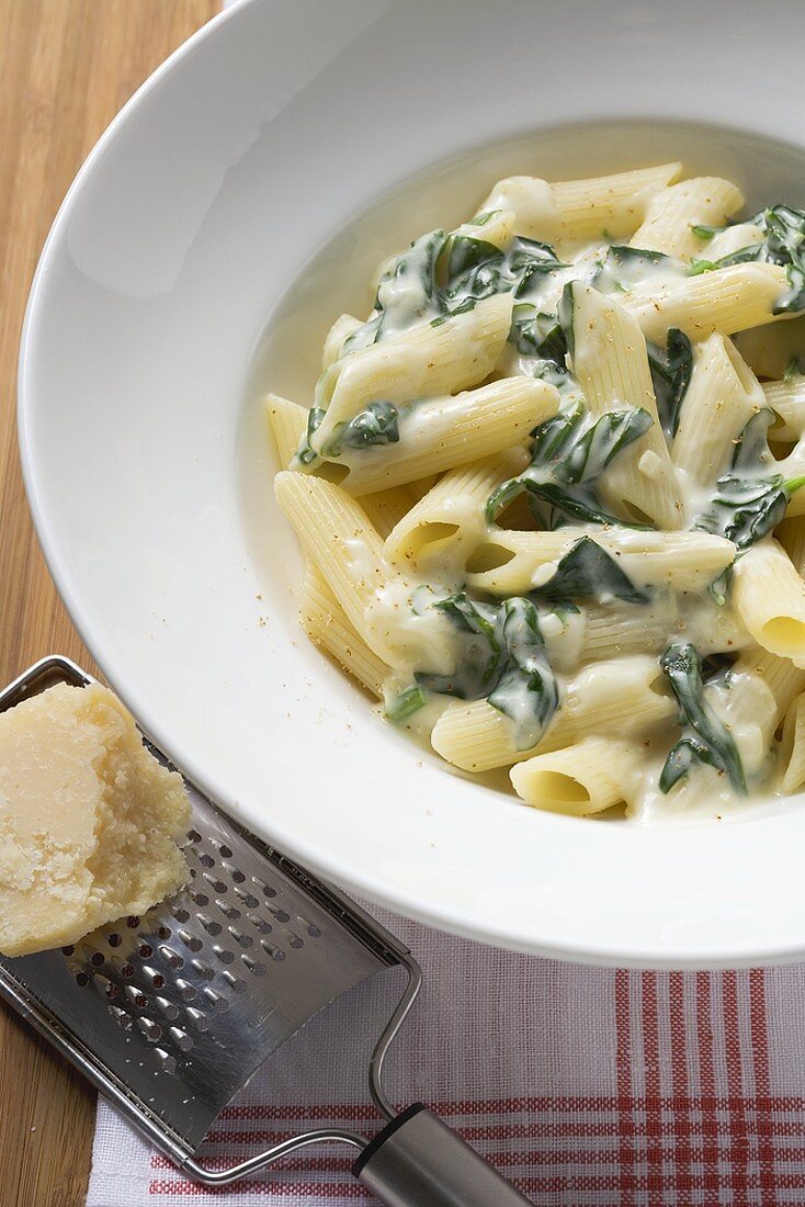 Penne rigate with spinach and cream sauce, Parmesan and grater