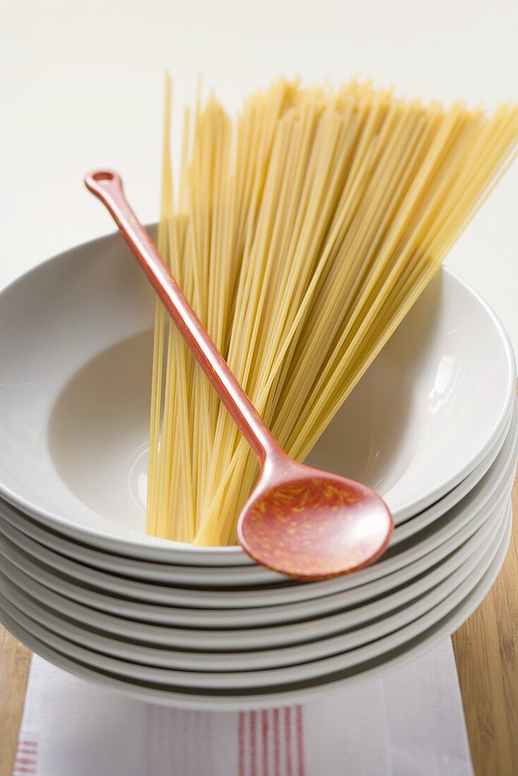 Spaghetti mit Kochlöffel auf Tellerstapel