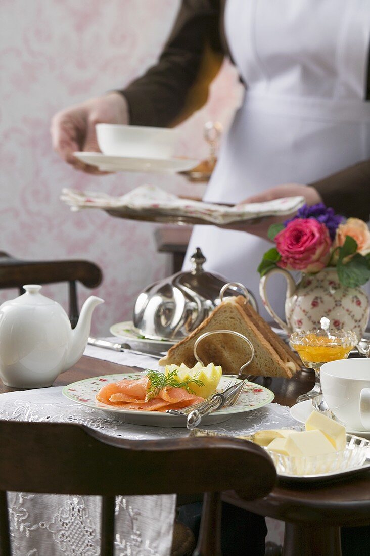 Tisch mit Räucherlachs & Toast, im Hintergrund Zimmermädchen