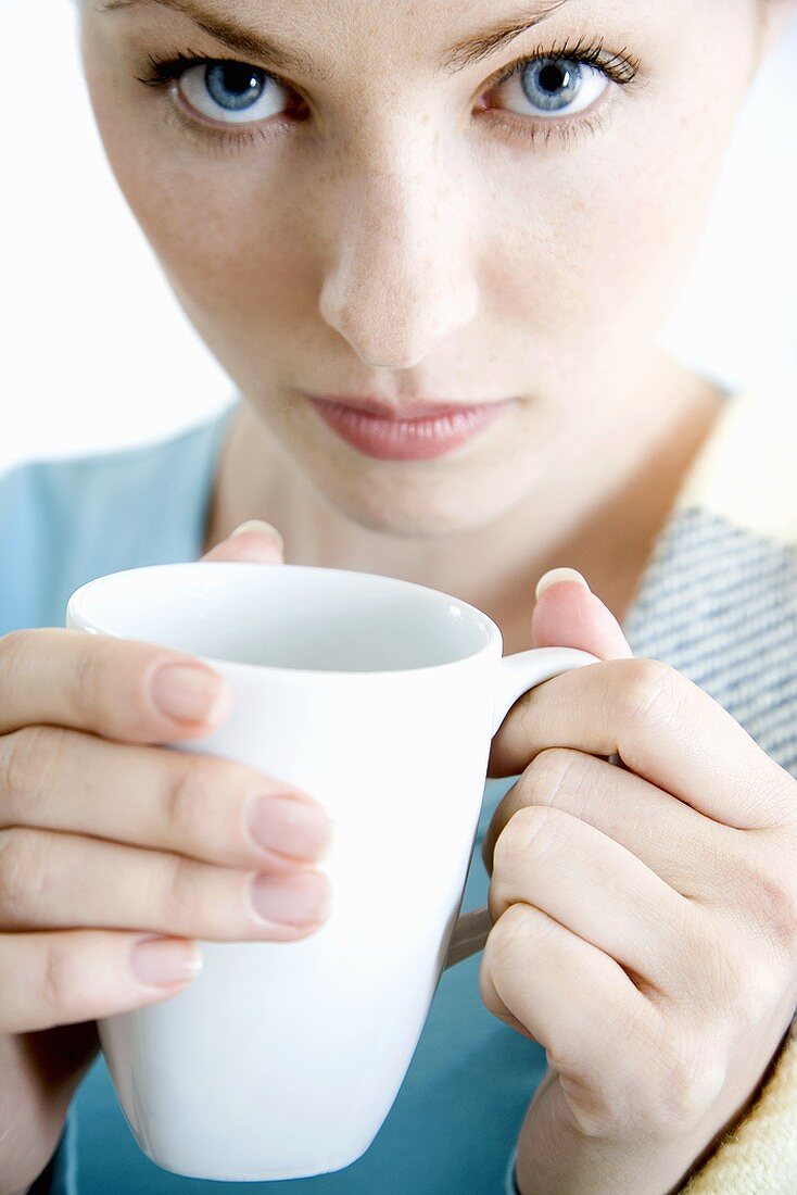 Junge Frau hält eine Tasse in der Hand